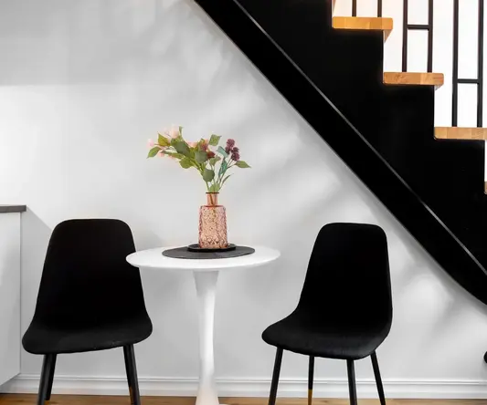 a table with chairs and a vase of flowers