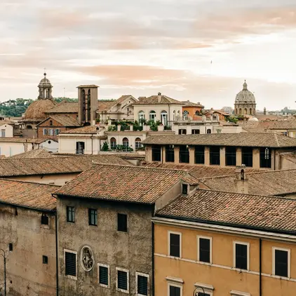 a rooftops of buildings with a city in the background by Gabriella Clare Marino