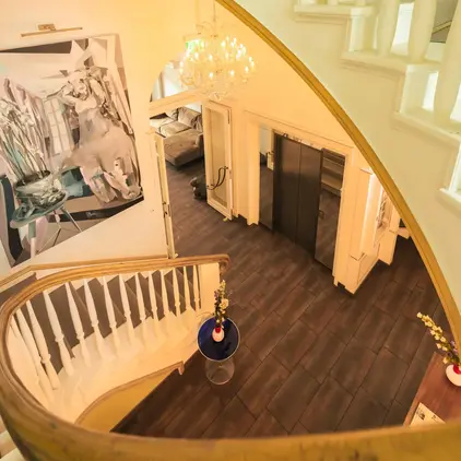 a staircase with a chandelier and art on the wall