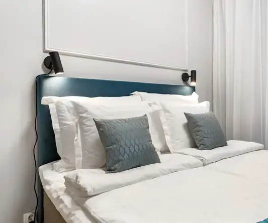a bed with white sheets and pillows