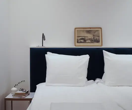 a bed with white pillows and a picture on the wall
