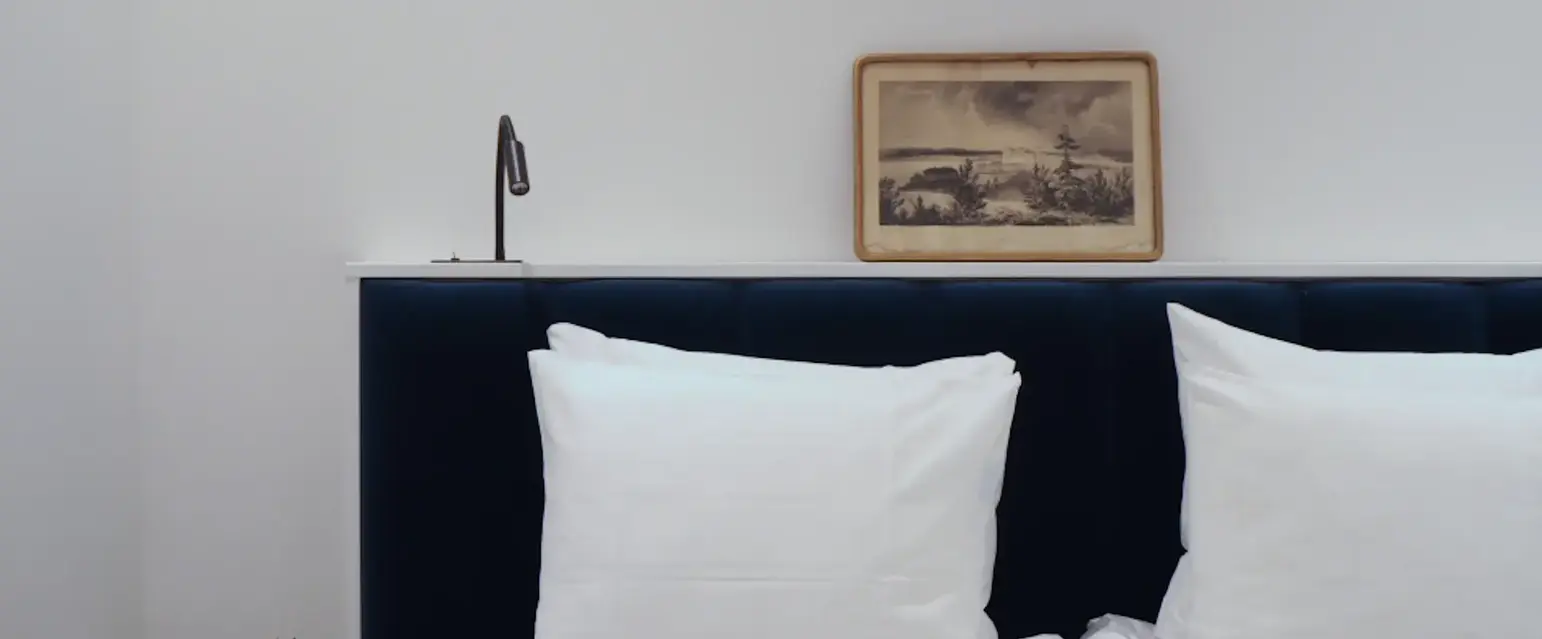 a bed with white pillows and a picture on the wall