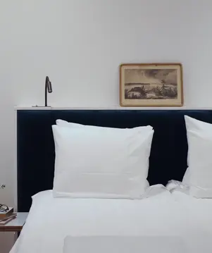a bed with white pillows and a picture on the wall