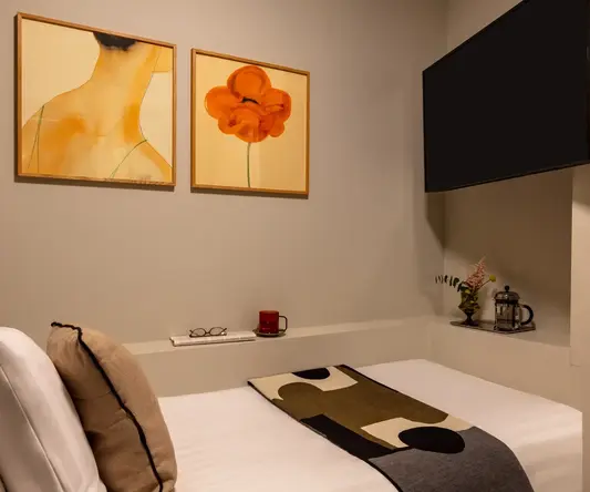 a bed with a blanket and a painting on the wall