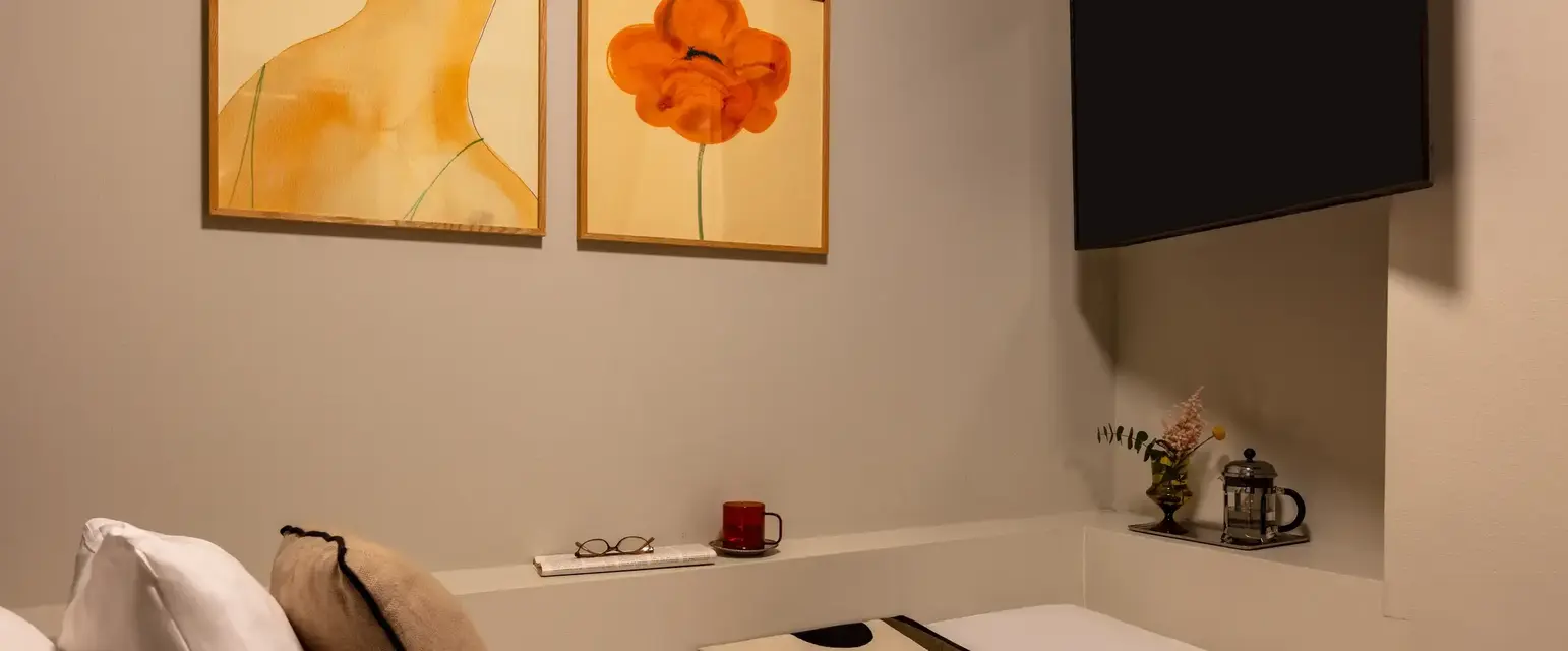 a bed with a blanket and a painting on the wall