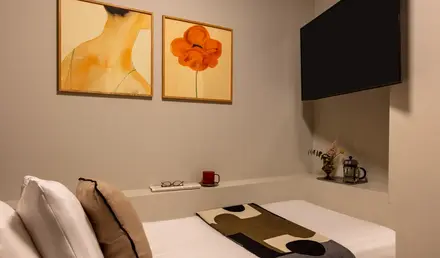 a bed with a blanket and a painting on the wall