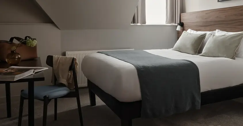 a bed with a chair and a desk in a room