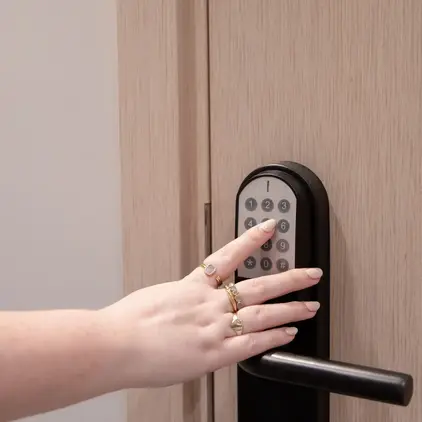 a hand with rings on a black door handle