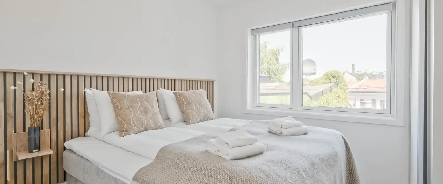 a bed with pillows and blankets in a room with windows