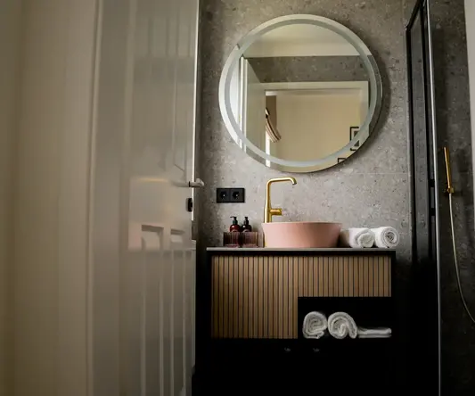 a bathroom with a round mirror and sink