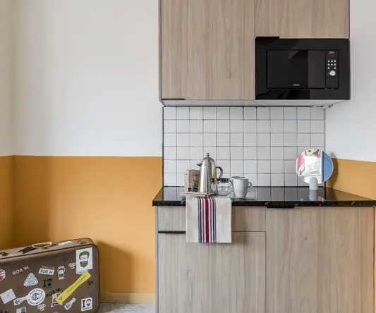 a kitchen with a microwave and a suitcase