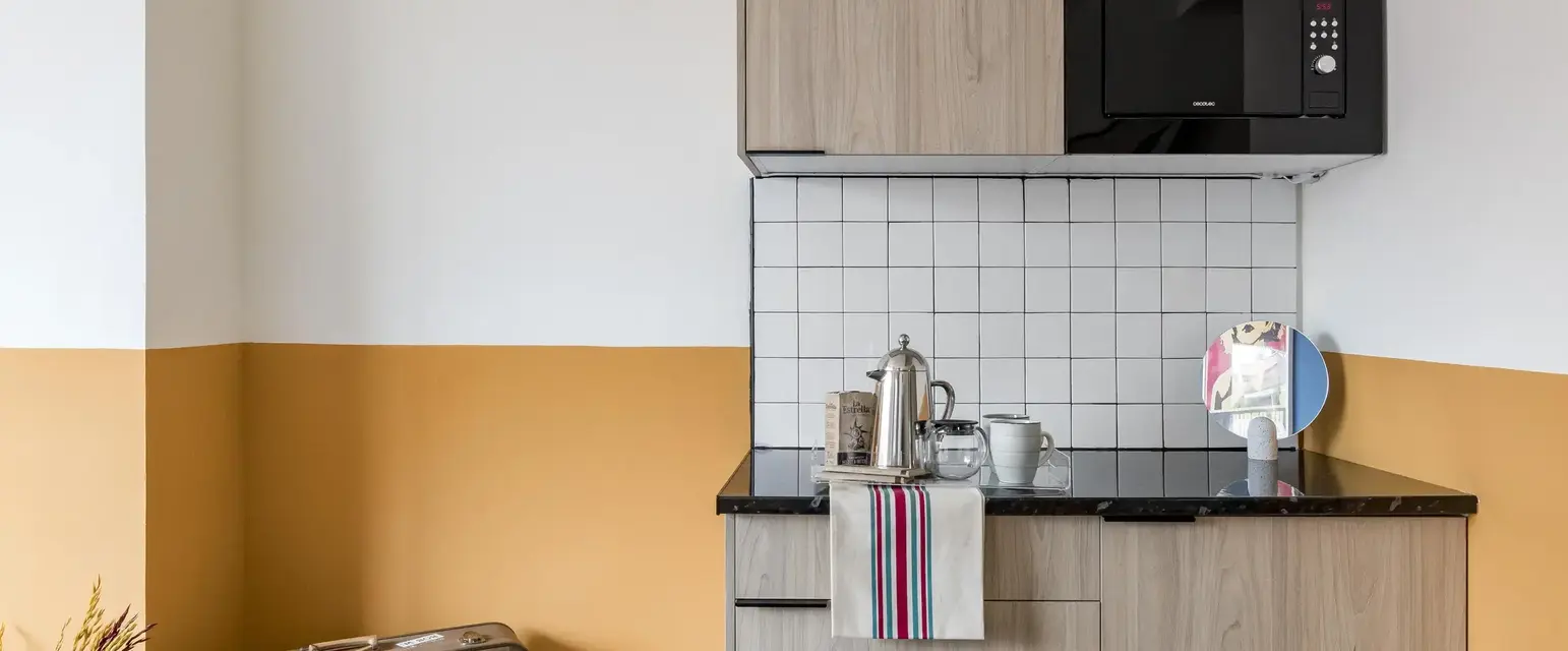 a kitchen with a microwave and a suitcase