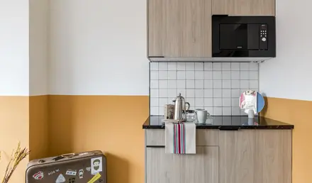 a kitchen with a microwave and a suitcase
