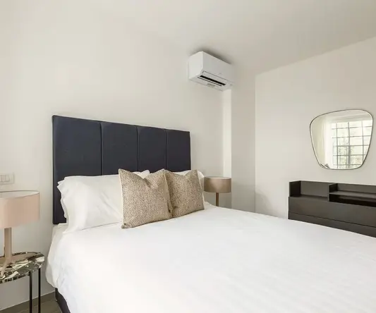 a bed with pillows and a mirror in a room