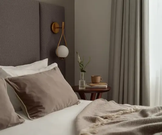 a bed with pillows and a vase of flowers on a table