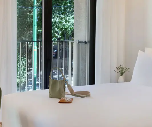 a bed with a white sheet and a purse on it