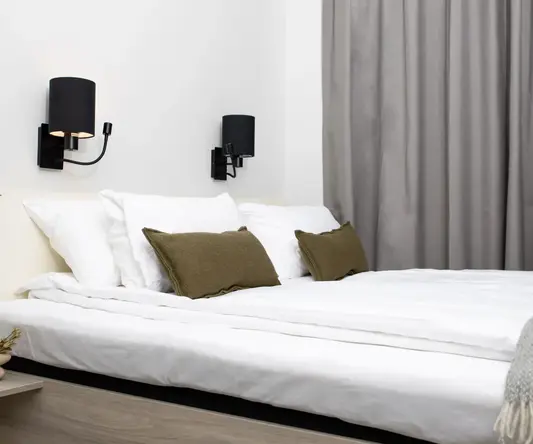 a bed with white sheets and brown pillows
