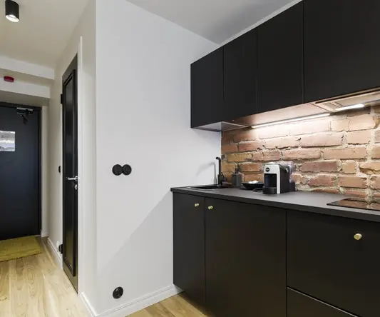 a kitchen with black cabinets and brick wall
