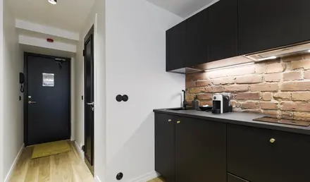a kitchen with black cabinets and brick wall