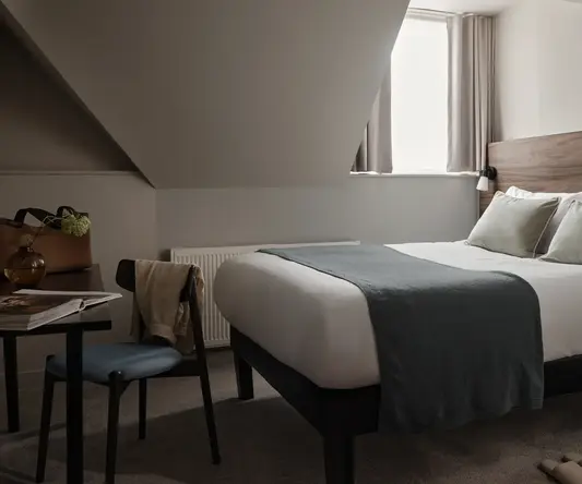 a bed with a chair and a desk in a room