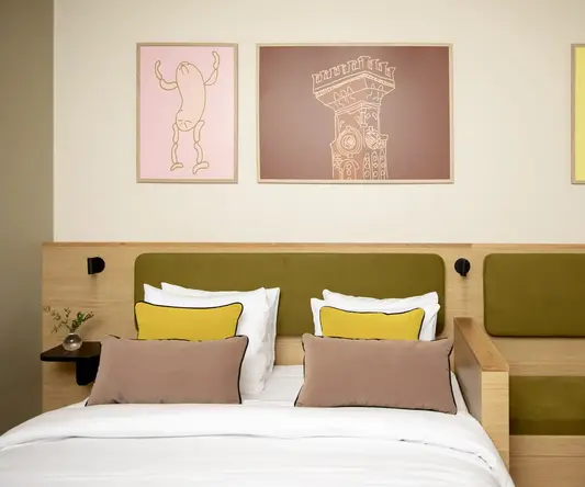 a bed with pillows and a chair in front of a wall with pictures