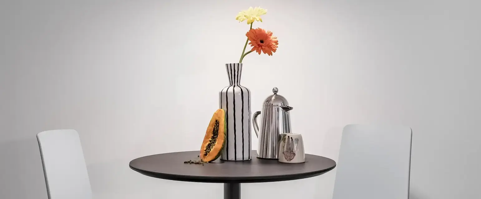 a table with chairs and a vase of flowers