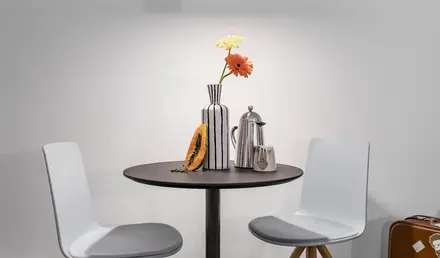 a table with chairs and a vase of flowers
