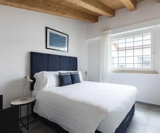 a bed with white sheets and blue headboard in a room