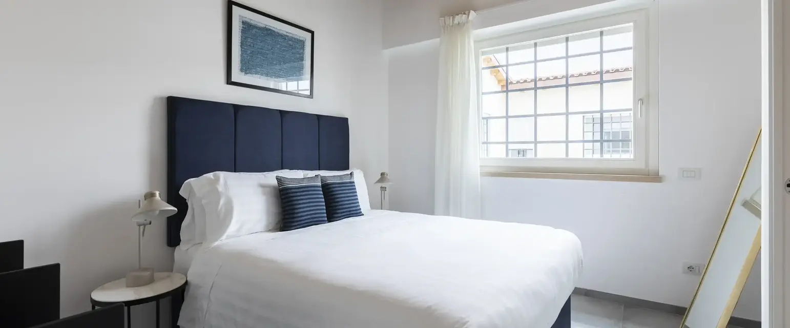 a bed with white sheets and blue headboard in a room