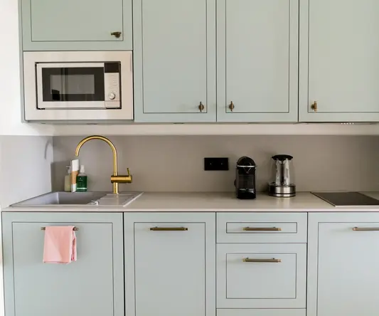 a kitchen with white cabinets and a gold faucet