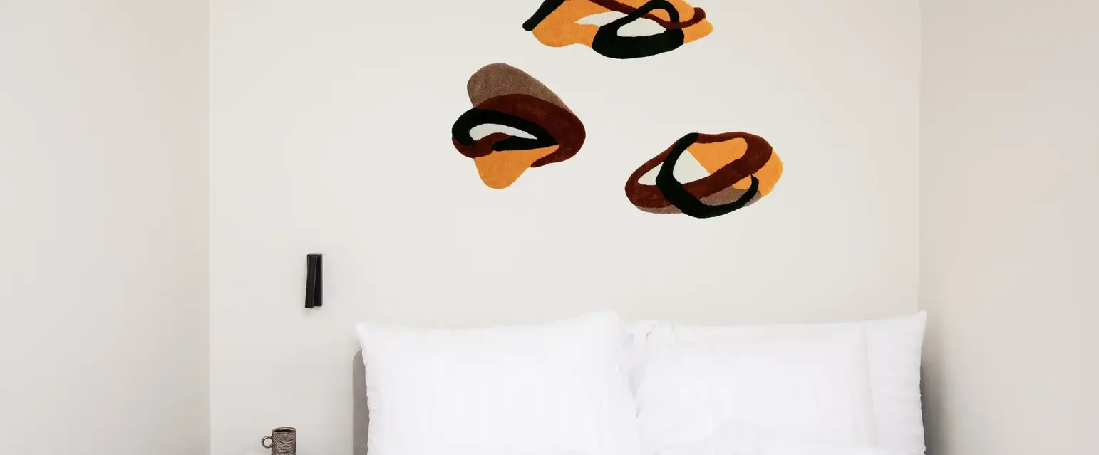 a bed with pillows and a coffee cup on the side