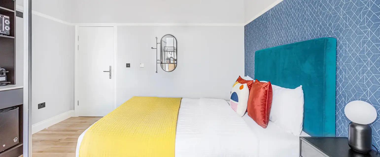 a bed with a blue headboard and yellow and red pillows
