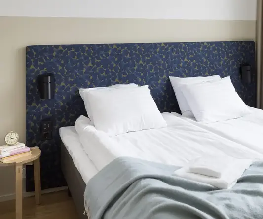 a bed with white sheets and a blue headboard