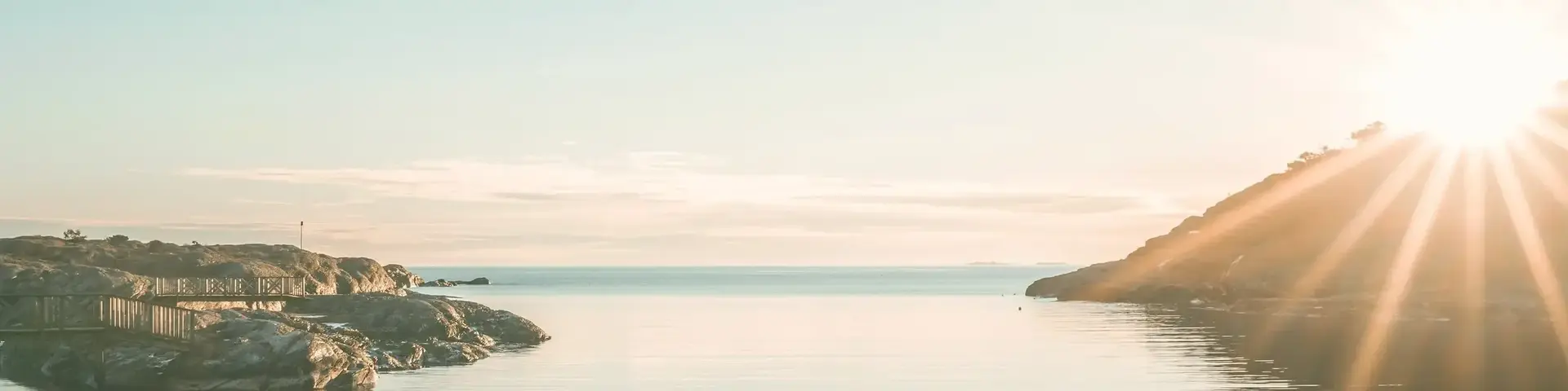 a body of water with rocks and a hill in the background