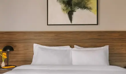 a bed with white sheets and a painting on the wall