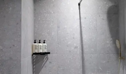 a shower with a couple of white bottles on a shelf