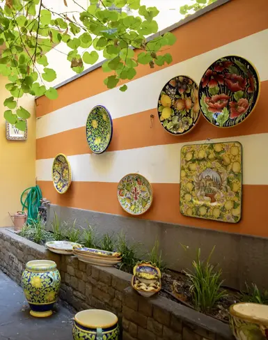 a courtyard with a wall of plates and vases