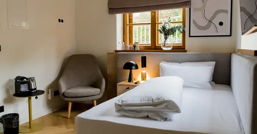 a bed with a lamp and a chair in a room