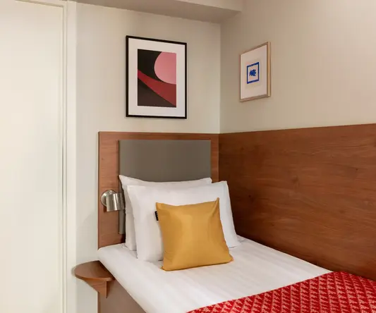 a bed with a red blanket and a gold pillow