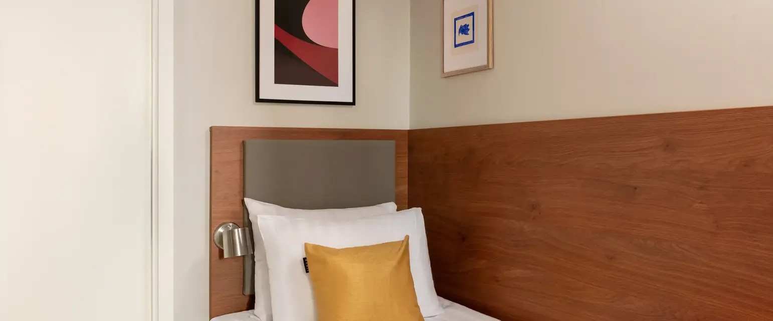 a bed with a red blanket and a gold pillow