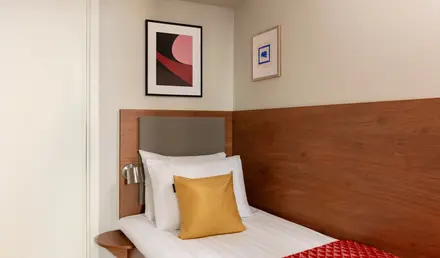 a bed with a red blanket and a gold pillow