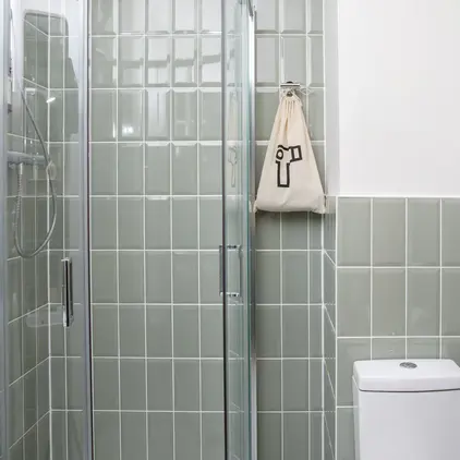 a shower with glass doors and a bag on the wall
