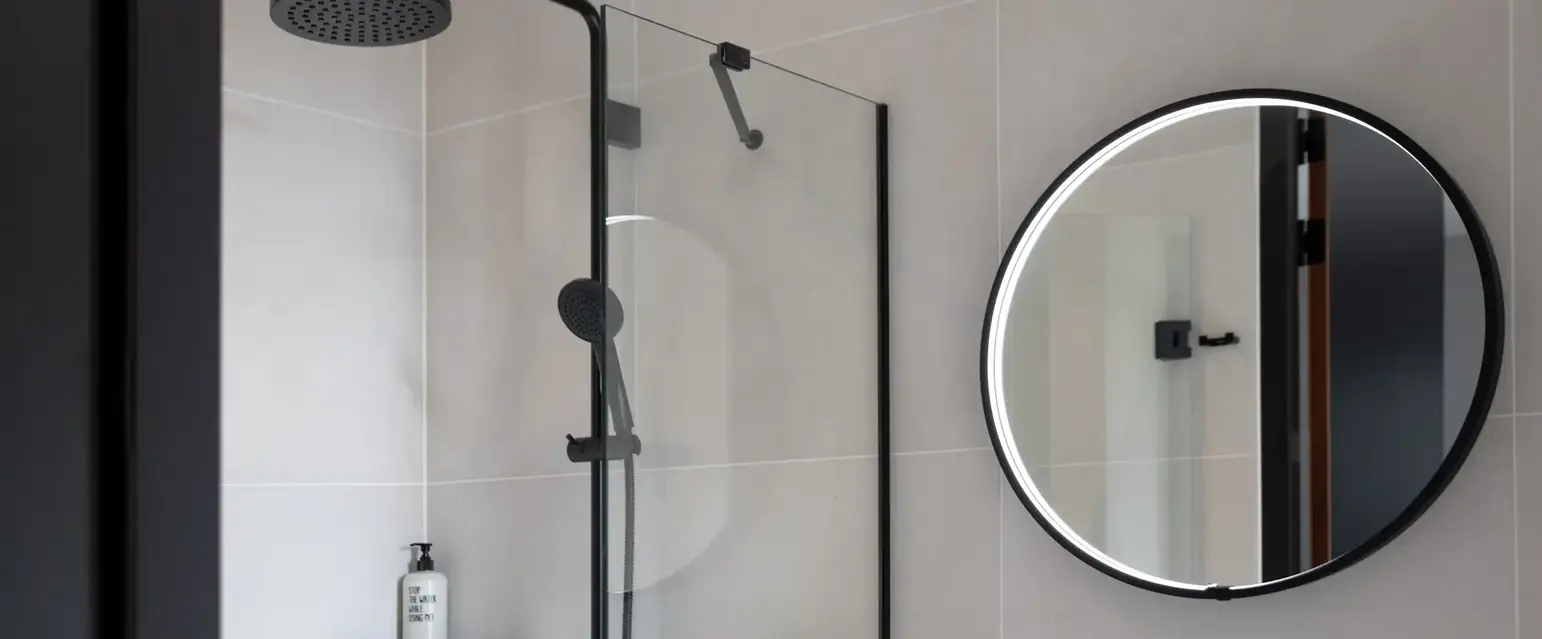 a shower with a round mirror