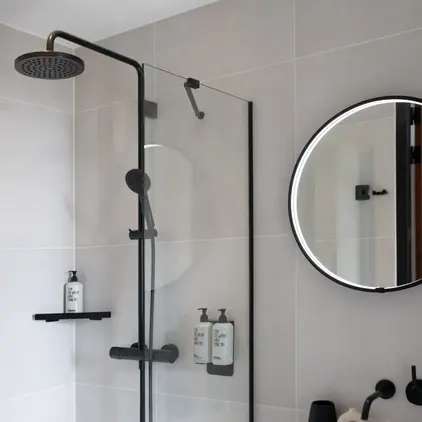 a shower with a round mirror