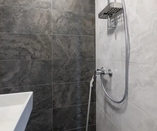 a shower with a hose and a sink