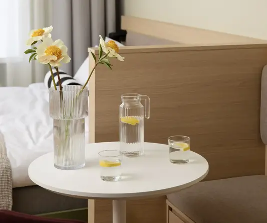 a table with a vase of water and flowers on it