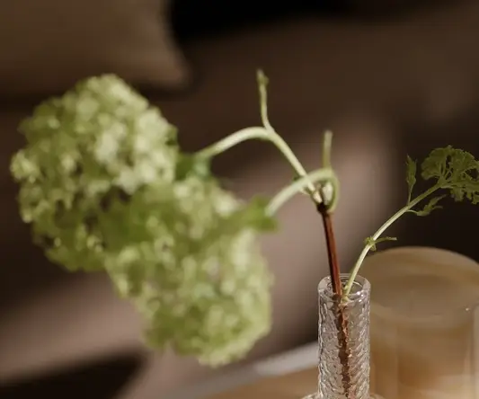 a glass vase with a stem in it and a candle on a table