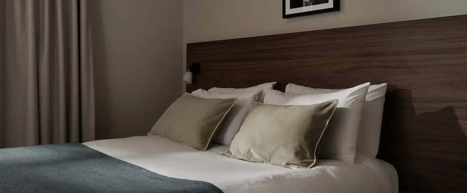 a bed with pillows and a lamp on the side