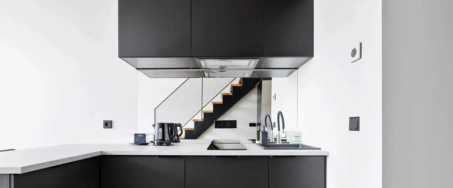 a kitchen with black cabinets and a staircase