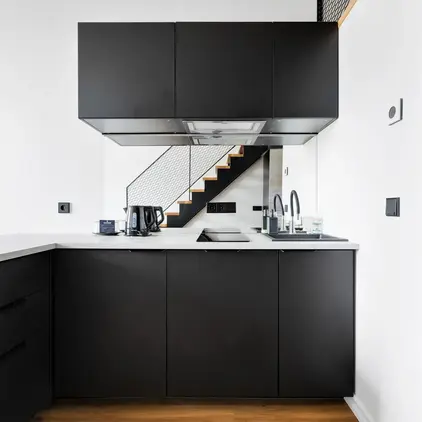 a kitchen with black cabinets and a staircase